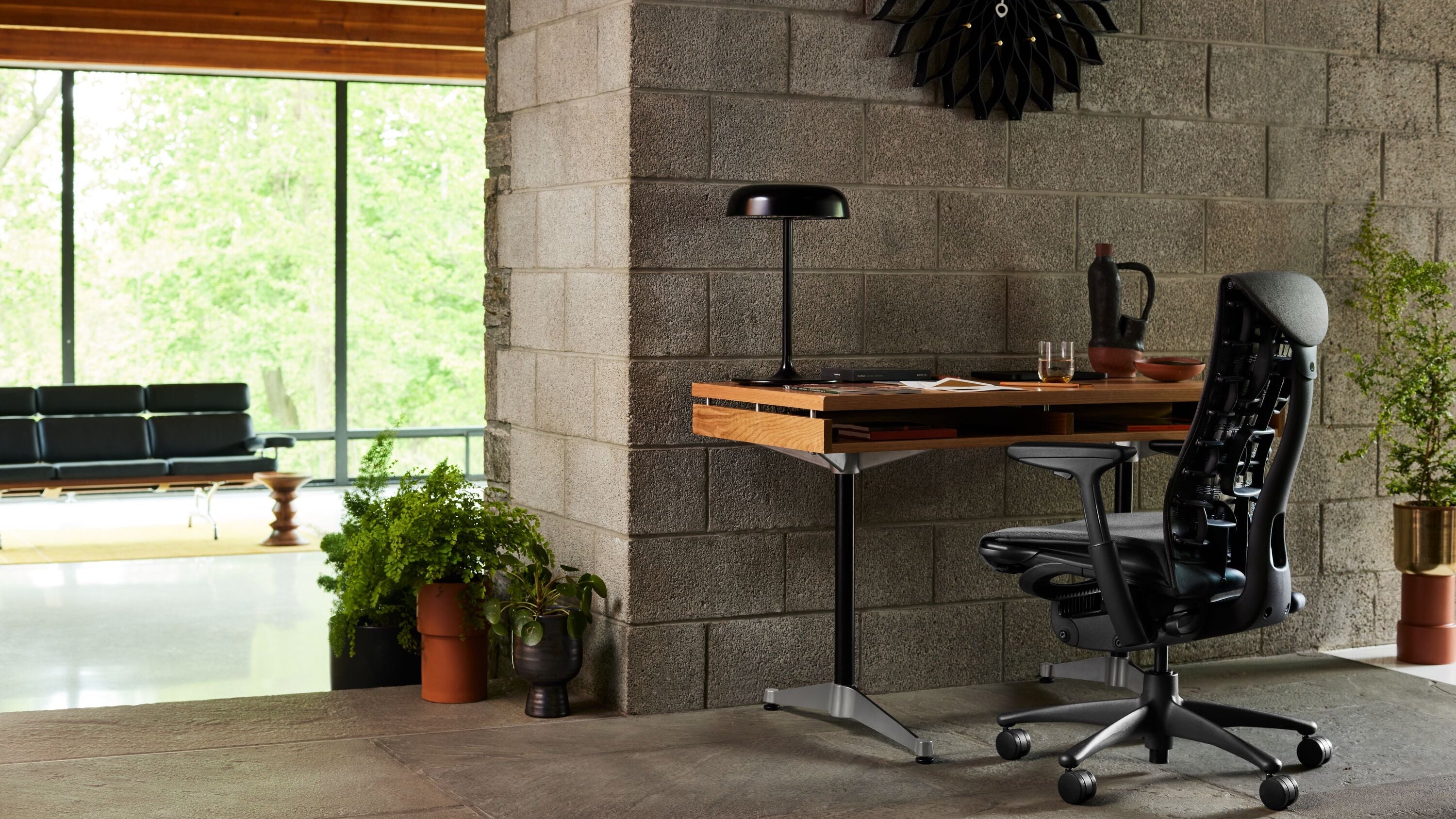 An AbakEnvironments Desk with a walnut top and polished legs, with a graphite Aeron Chair in a light home office setting and Folk Ladder Shelving.