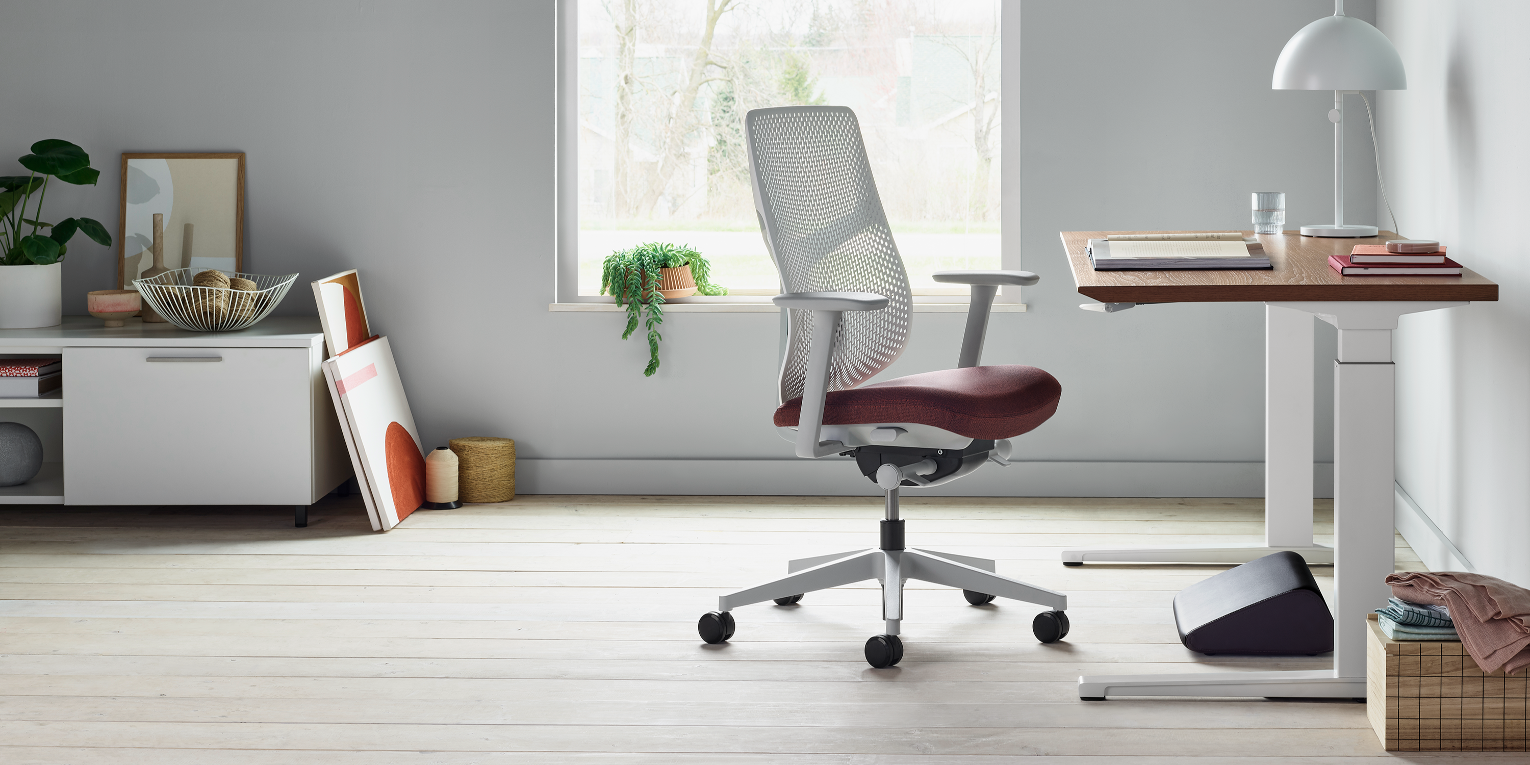 An AbakEnvironments Desk with a walnut top and polished legs, with a graphite Aeron Chair in a light home office setting and Folk Ladder Shelving.