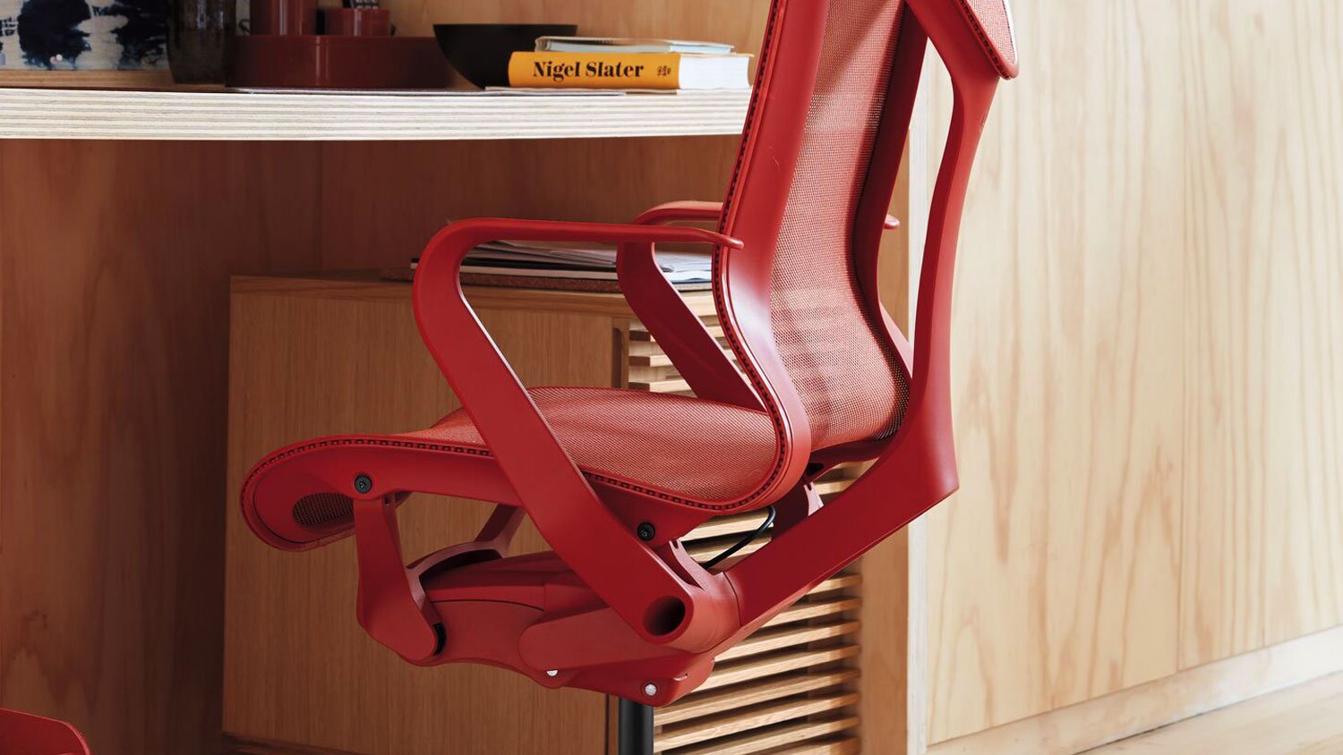 A close up of a red Cosm chair in front of a red back drop