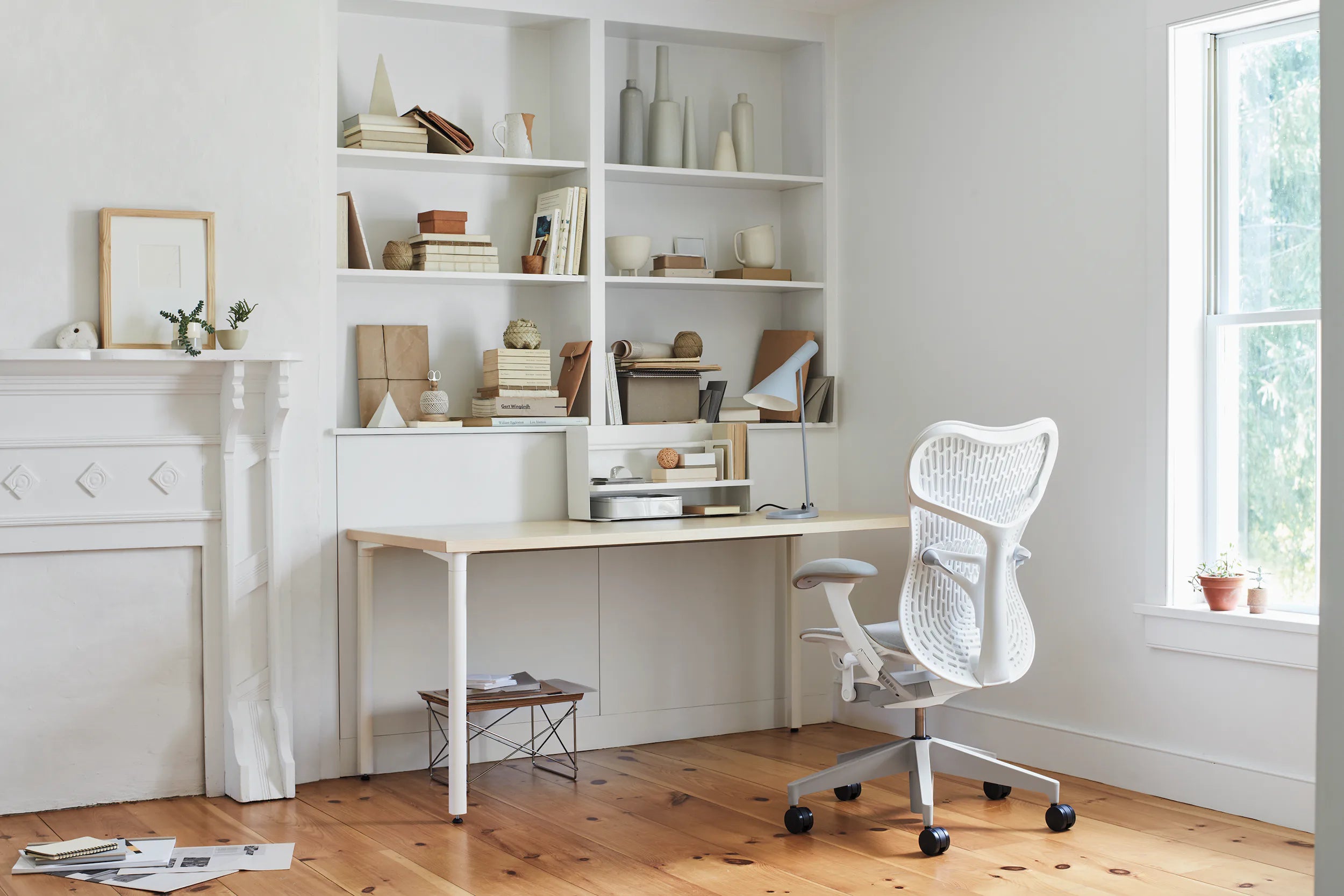 An AbakEnvironments Desk with a walnut top and polished legs, with a graphite Aeron Chair in a light home office setting and Folk Ladder Shelving.