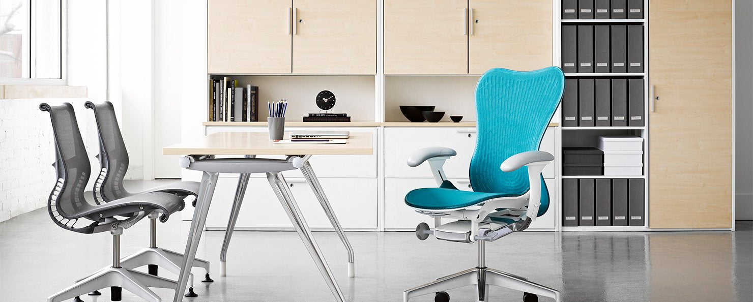 A blue Mirra 2 chair in an office environment alongside an Abak Environments desk and two grey Setu chairs.