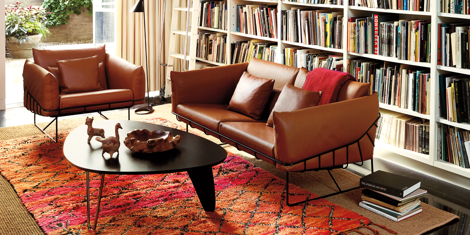 An AbakEnvironments Desk with a walnut top and polished legs, with a graphite Aeron Chair in a light home office setting and Folk Ladder Shelving.
