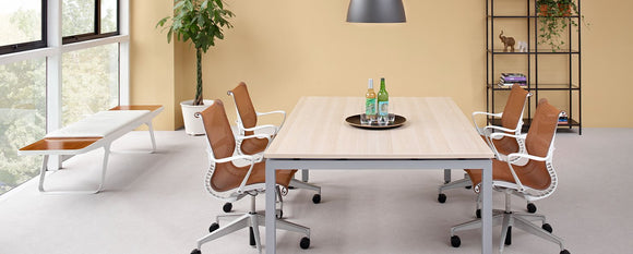 Orange Setu chairs gathered around a large meeting table.